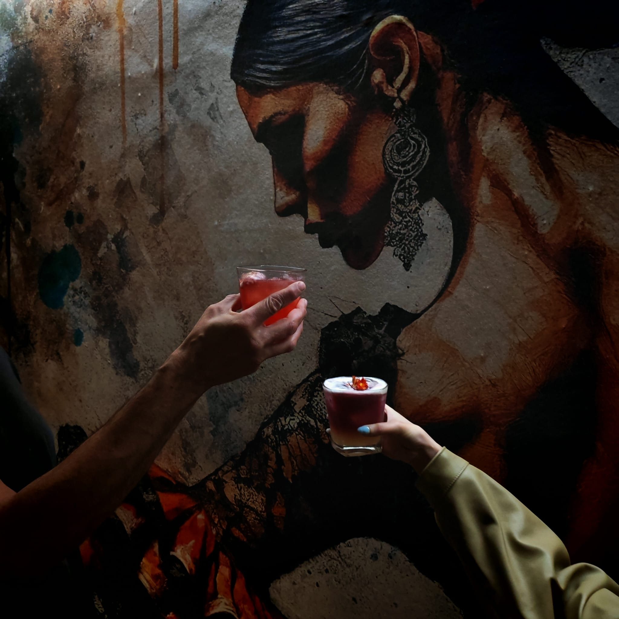 Guests raising cocktails beside the mural